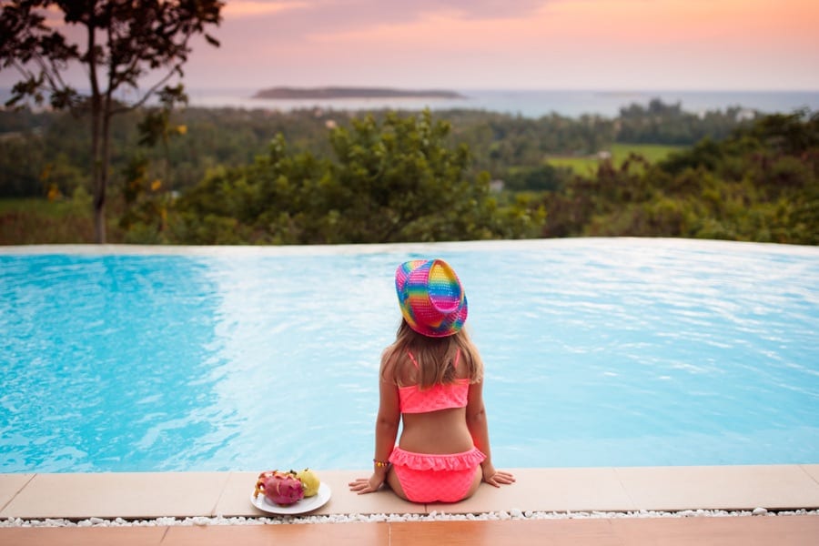 Little girl sitting by a swimming pool